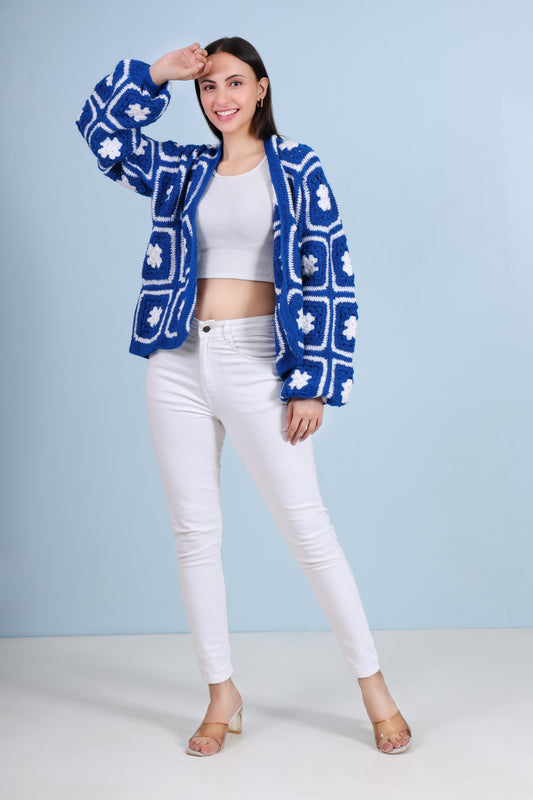 Woman wearing a blue floral jacket, white top, and white pants against a light blue background