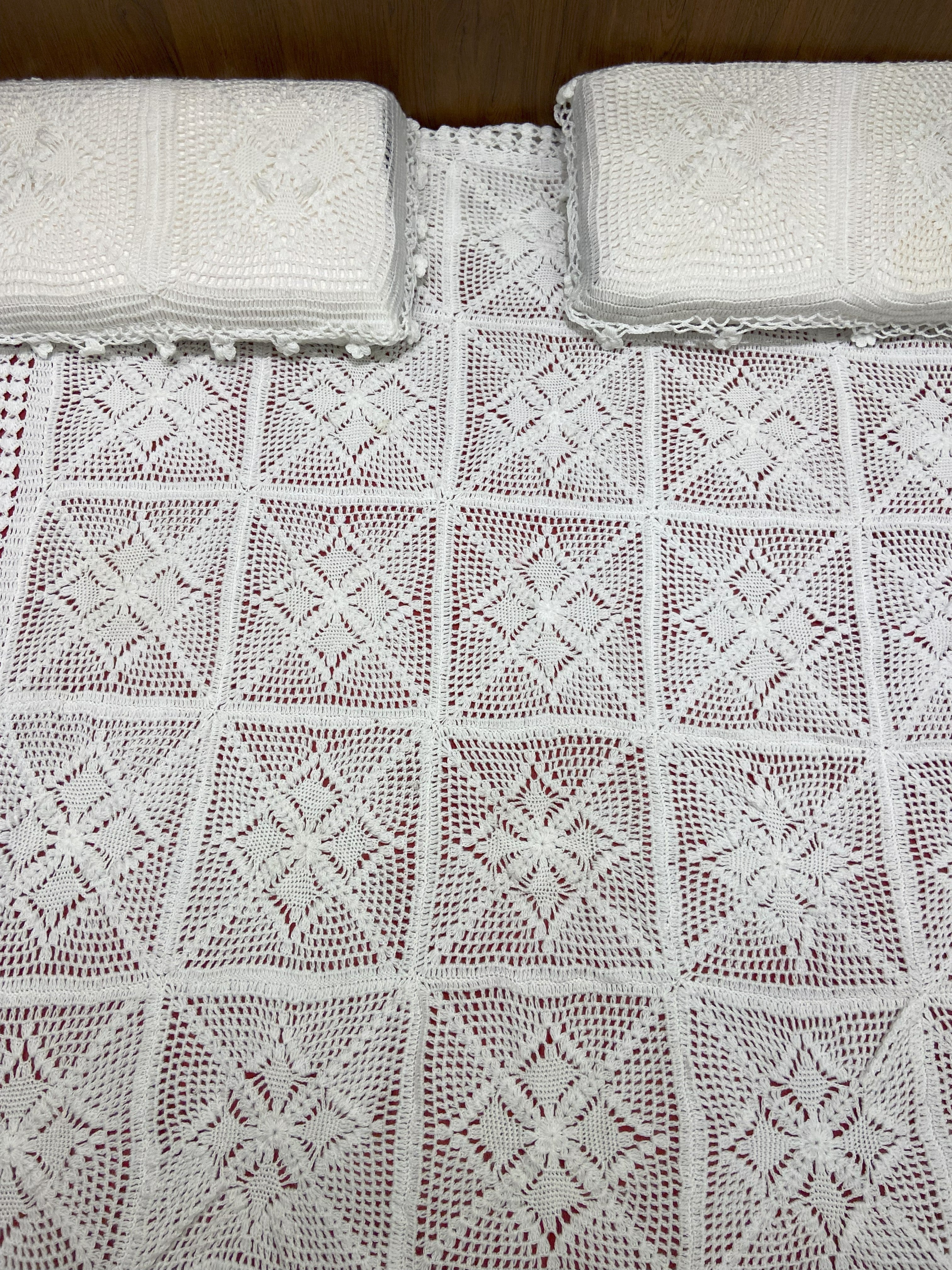 Knitted white blanket with a diamond pattern on a wooden surface